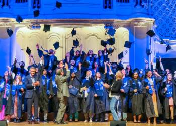 Etudiants diplômés sur une scène heureux jettent leurs chapeaux