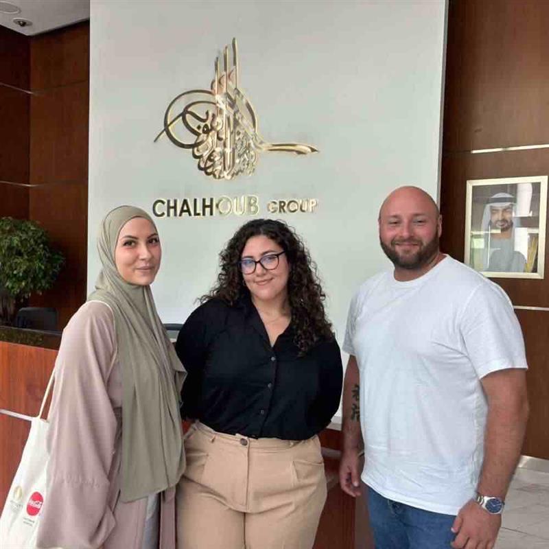 Un homme et deux femmes posent face à la caméra dans le hall d'une entreprise à Dubai